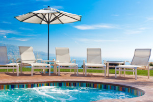 Jacuzzi pool, lounge chairs and umbrella with view of Pacific ocean